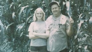 Girl standing with her father in front of corn stalks at Jacksonville wedding venue