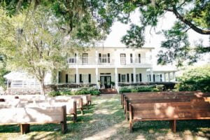 Pews lined up for wedding ceremony in front of manor house at All 4 One Farms