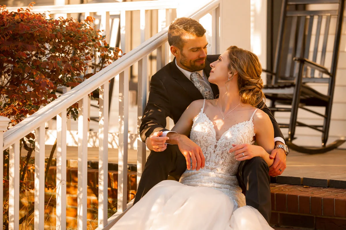 Bride and groom looking into each other's eyes seated on the steps of the main house at All 4 One Farms.