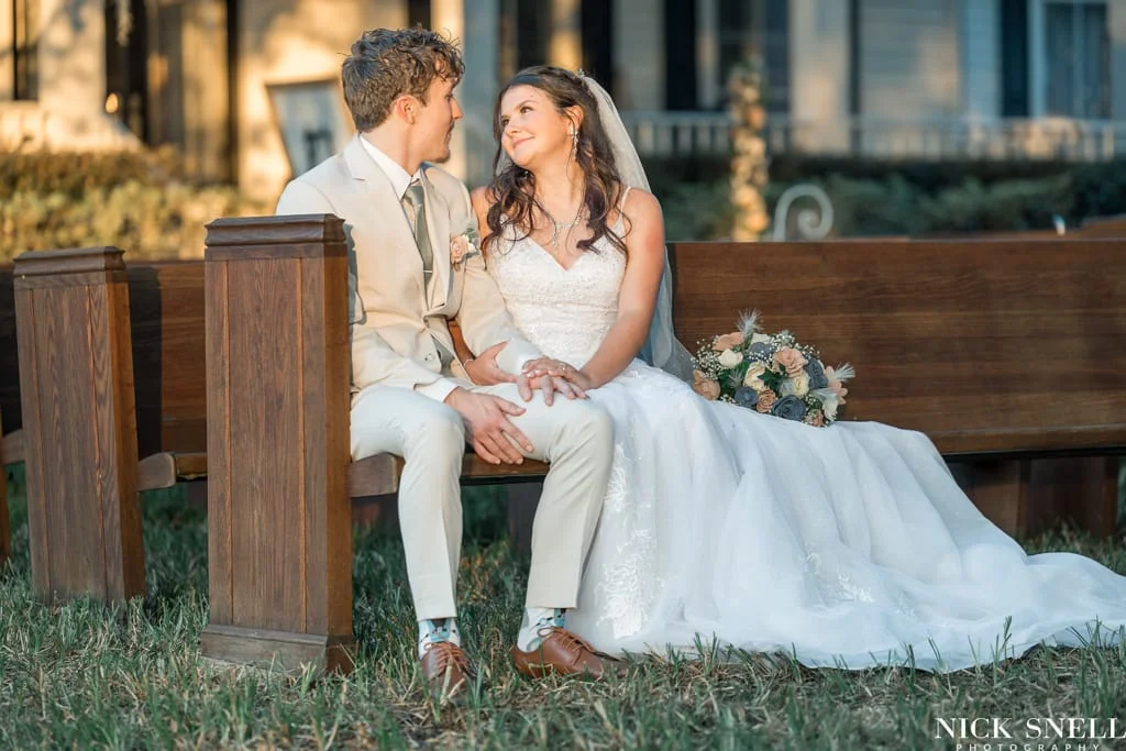 Bride looking into the groom's eye seated on the pew at All 4 One Farms