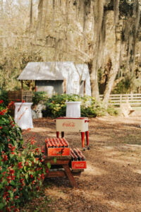 High top tables and Coke Cola cooler set up under oak trees