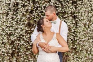 Bride and groom embrace in front of jasmine wall at All4One Farms wedding venue.