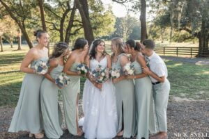 Bridal party surrounds the bride with looks of love. At All4One Farms wedding venue Jacksonville, FL