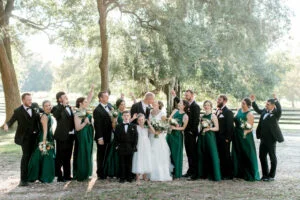 Bride and Groom kiss while the wedding party looks on. Under the oak trees at All4One Farms wedding venue