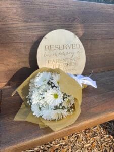 Bouquet of daisies on a wooden pew reserving a spot in memory of the bride's parents at All4One Farms in Jacksonville, FL.