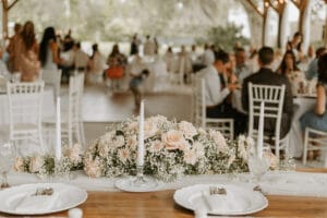 Sweetheart table with beautiful florals and china and in the background the wedding guests seated at their tables during the reception.