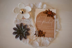 wedding invitation along with a string of pearls and perfume