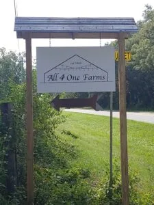 Roadside sign for All4One Farms along county road 218.