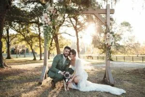 Bride and Groom kneeling down with their dog just after their wedding ceremony at All4One Farms.