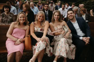 Wedding guests sitting on oak pews before the ceremony at All4One Farms
