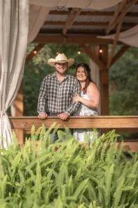 Bride and groom looking out from the reception barn with ferns in front of them.