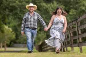 Engaged couple walking happily along the fence at All4One Farms