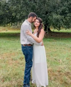 Bride and groom embrace in front of an oak tree at All4One Farms