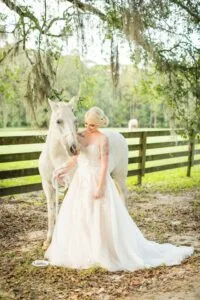 Bride and white horse in front of fence at Jax wedding venue.