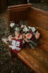 Bouquet and rings on an oak pew at Jax wedding venue.